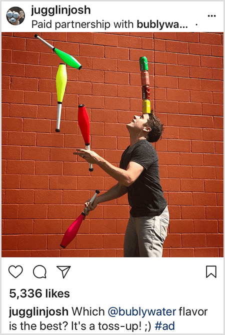 Josh Horton žonglira s palicami, ki se ujemajo z barvami štirih vodnih pločevink Bubly, zloženih na njegovo glavo. Ozadje je rdeča opečna stena. Fotografija je oglas, ki ga je Josh ustvaril za vodo Bubly in ga objavil v svojem viru na Instagramu z opisom Kateri okus okusa vode je najboljši? To je premetavanje!